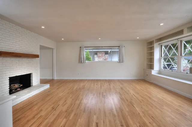 a view of a livingroom with wooden floor and a fireplace