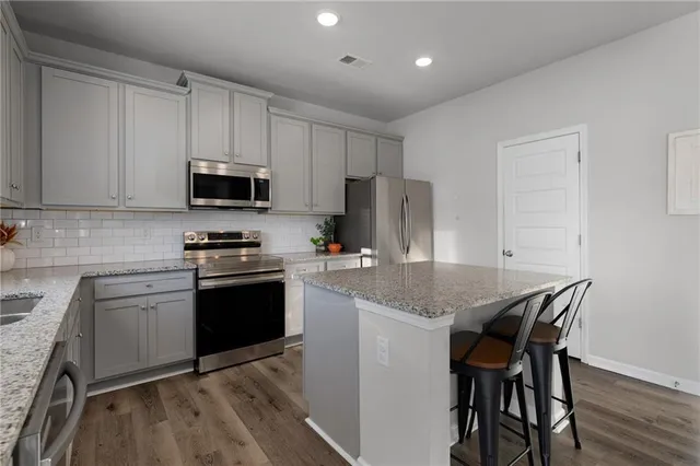 a kitchen with stainless steel appliances kitchen island granite countertop a table chairs microwave and sink