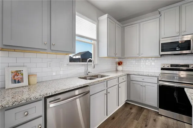 a kitchen with stainless steel appliances granite countertop a sink a stove and cabinets