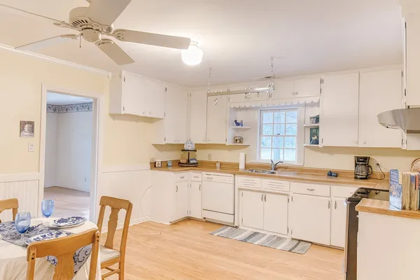 a kitchen with stainless steel appliances granite countertop a sink a stove a refrigerator cabinets and chairs