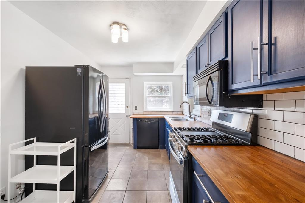 4088 Howley Street Pittsburgh, PA 15224 - Photo 14 of 32 a kitchen with stainless steel appliances granite countertop a refrigerator a stove and a sink with wooden cabinets