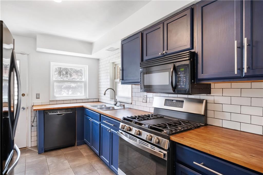 4088 Howley Street Pittsburgh, PA 15224 - Photo 10 of 32 a kitchen with stainless steel appliances granite countertop a stove a sink dishwasher and a microwave oven with wooden cabinets