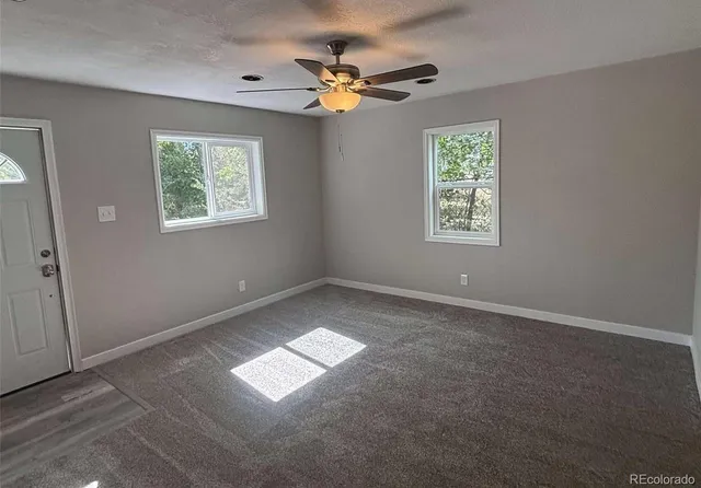 an empty room with windows and fan