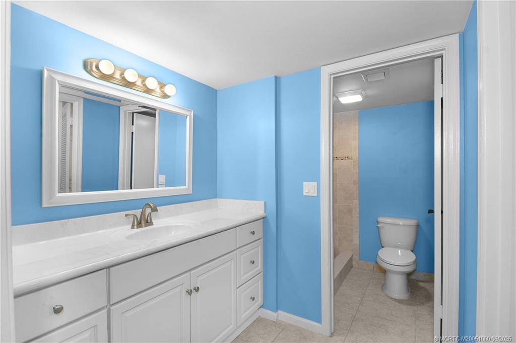 3100 Southeast Pruitt Road, Unit B105 Port St. Lucie, FL 34952 - Photo 14 of 40 a bathroom with a toilet a sink a vanity and mirror