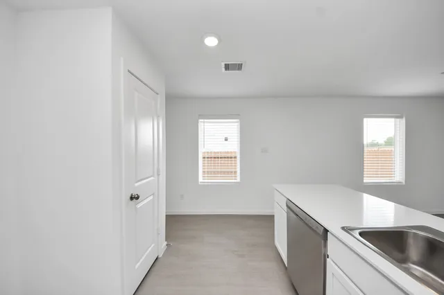 a view of a kitchen from the hallway with windows