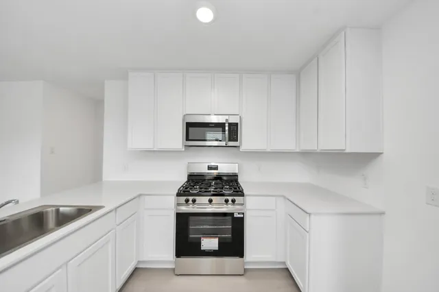 a kitchen with white cabinets and black appliances