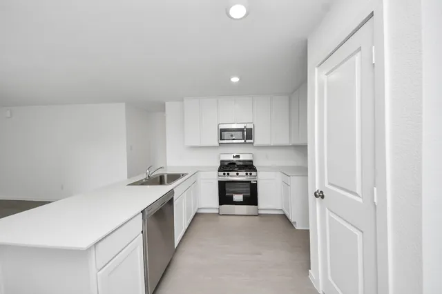 a kitchen with stainless steel appliances a refrigerator sink and white cabinets