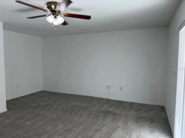 an empty room with a window and a fan