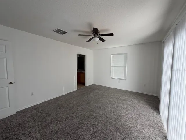 a view of an empty room and a ceiling fan and window