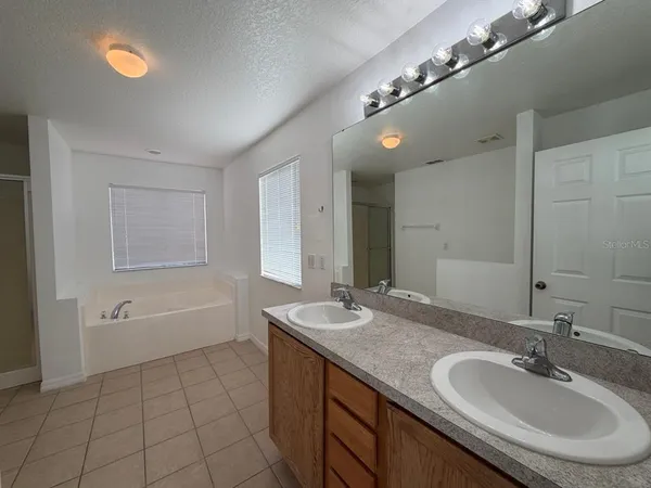 a bathroom with a granite countertop double vanity sink a mirror and a bathtub