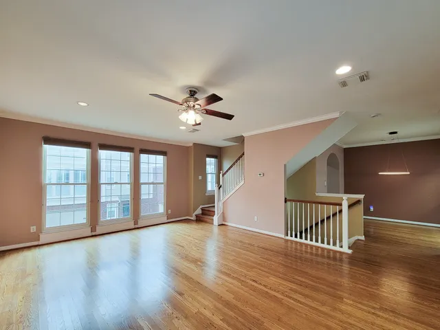 a view of an empty room with a window and wooden floor