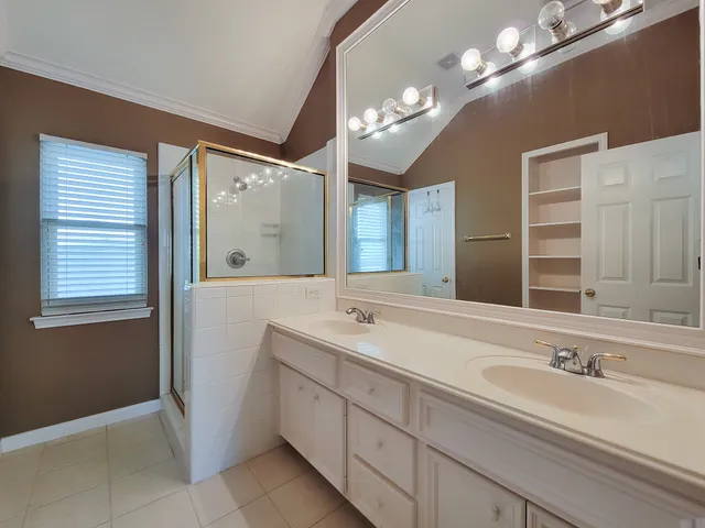 a spacious bathroom with a double vanity sink a mirror and a shower