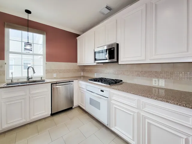 a kitchen with granite countertop white cabinets white stainless steel appliances and a sink