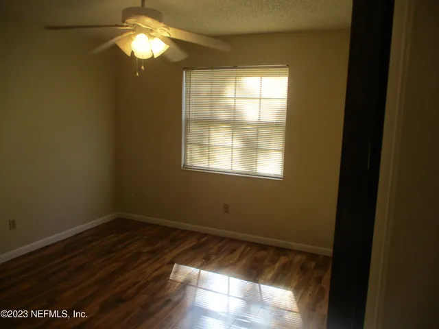 a view of empty room with wooden floor and fan