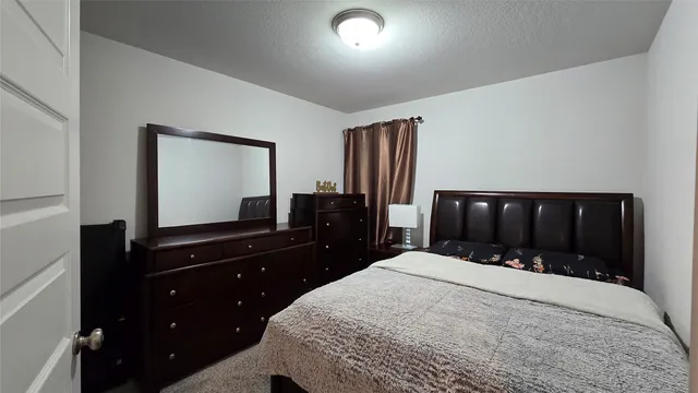 a bedroom with a bed and a flat tv screen on dresser