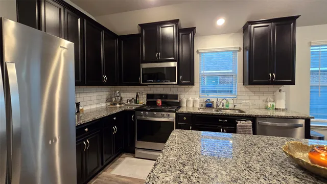 a kitchen with stainless steel appliances granite countertop a refrigerator a stove a sink and a microwave