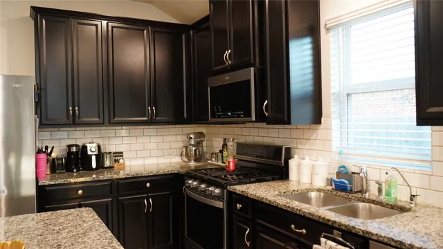 a kitchen with granite countertop a sink stove and cabinets