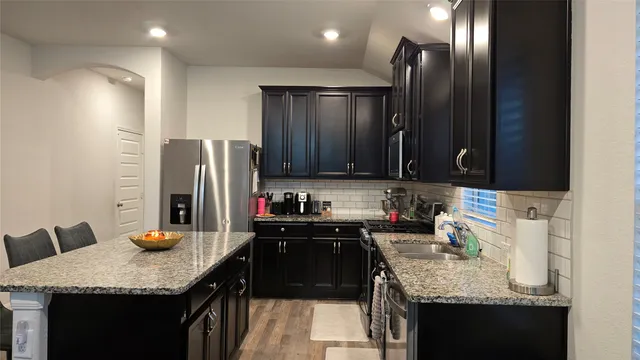 a kitchen with stainless steel appliances granite countertop a sink refrigerator and cabinets