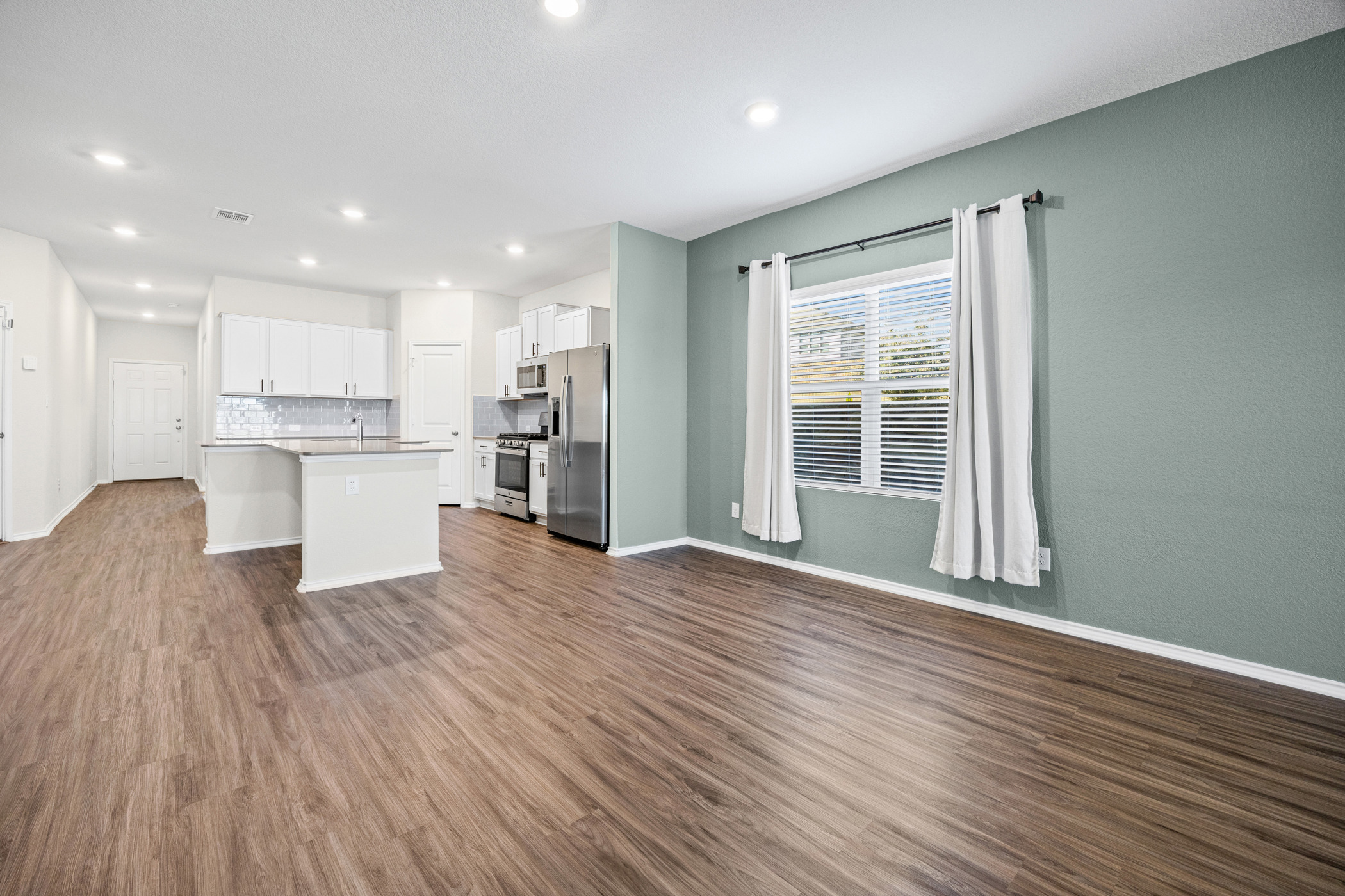 1609 Woolsey Way Leander, TX 78641 - Photo 29 of 29 Kitchen featuring open floor plan, white cabinets, a center island with sink, dark wood-style flooring, and stainless steel appliances