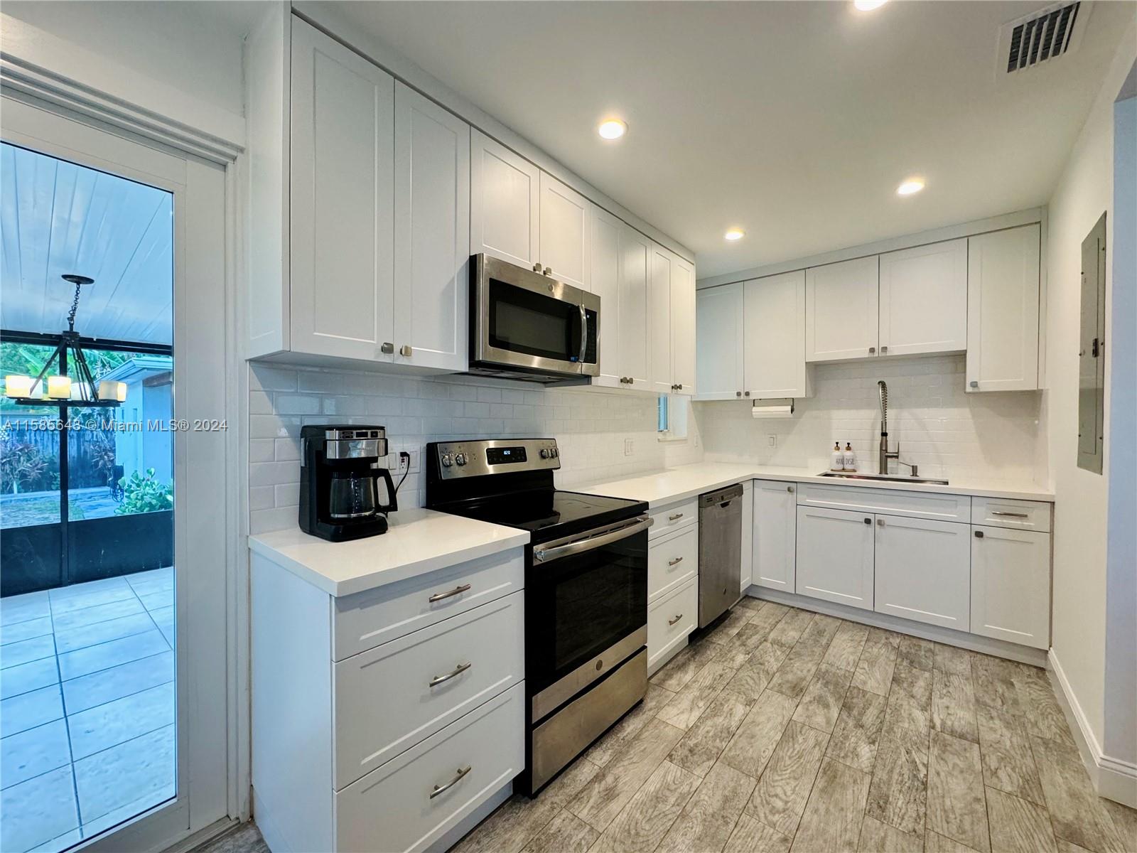 4235 Southwest 14th Street Miami, FL 33134 - Photo 2 of 32 a kitchen with granite countertop white cabinets and stainless steel appliances