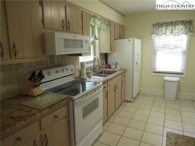 a kitchen with granite countertop a sink a stove a refrigerator and cabinets