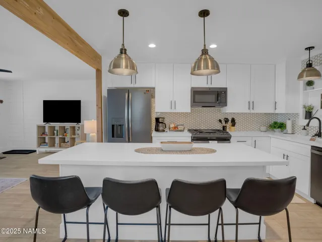 a kitchen with stainless steel appliances a dining table chairs and granite counter tops