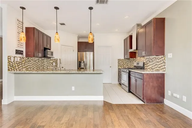 a kitchen with stainless steel appliances granite countertop a sink a stove and a wooden floors