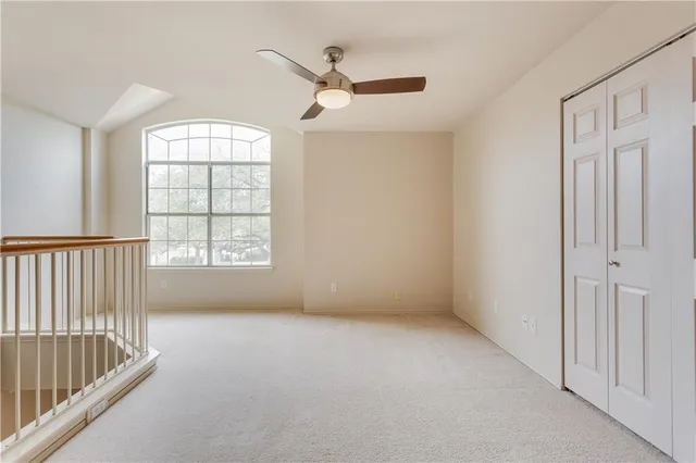 an empty room with windows and ceiling fan