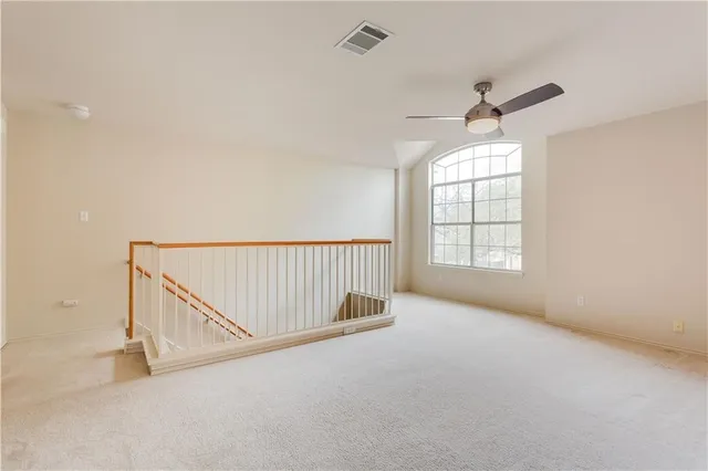 an empty room with windows and ceiling fan view