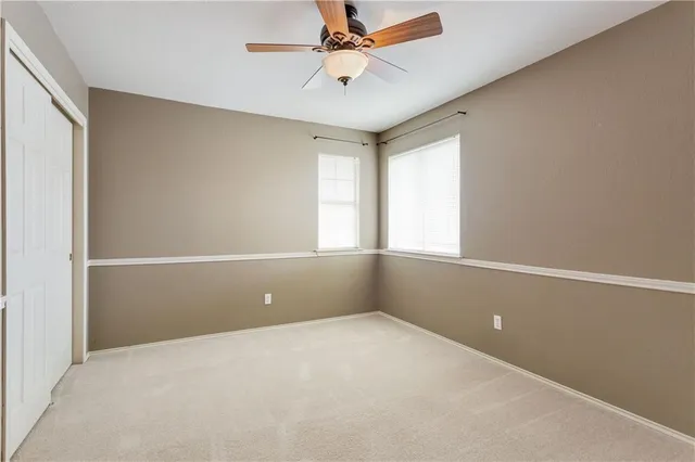 an empty room with windows and ceiling fan