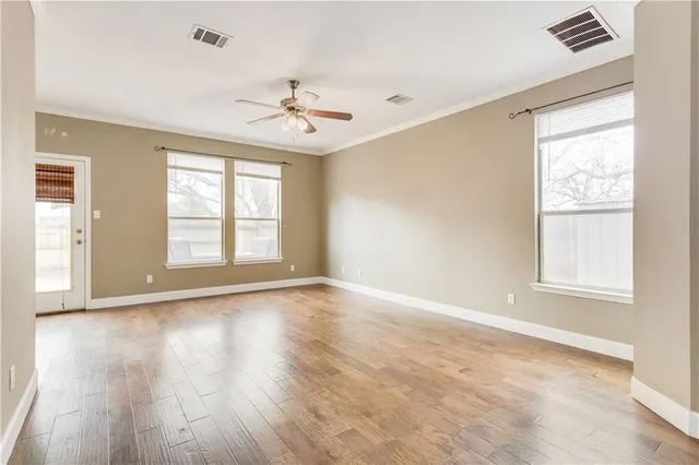 a view of an empty room with a window and wooden floor