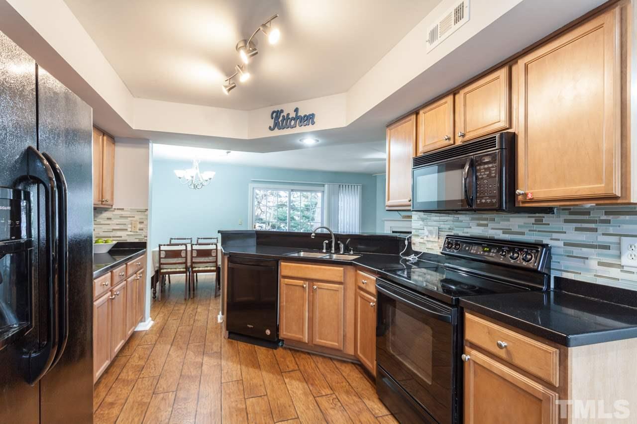 7900 Falcon Rest Circle, Unit 10 Raleigh, NC 27615 - Photo 14 of 25 a kitchen with stainless steel appliances granite countertop a stove a sink and a microwave
