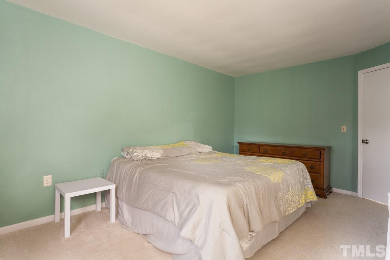 7900 Falcon Rest Circle, Unit 10 Raleigh, NC 27615 - Photo 18 of 25 a large bed sitting in a bedroom next to a wooden cabinet