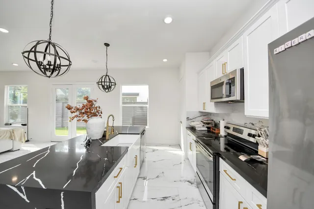 a kitchen with granite countertop stainless steel appliances a stove a sink a refrigerator and a dining table with wooden floor