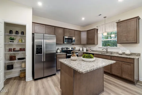 a kitchen with granite countertop stainless steel appliances a refrigerator a sink a stove a refrigerator cabinets and wooden floor