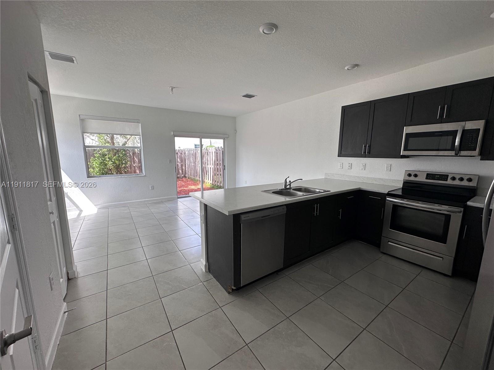 1884 Southeast 27th Street Homestead, FL 33035 - Photo 7 of 34 a kitchen with stainless steel appliances granite countertop a stove a sink and a microwave