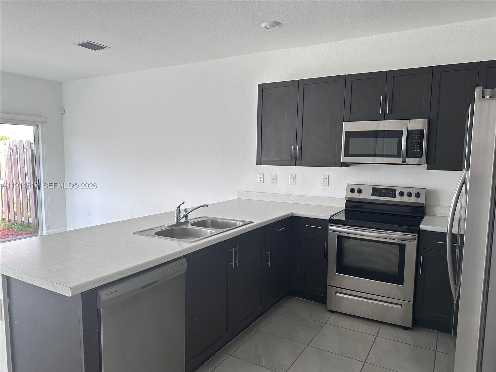 1884 Southeast 27th Street Homestead, FL 33035 - Photo 9 of 34 a kitchen with a sink stove and microwave