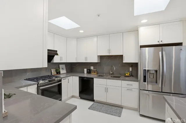 a kitchen with stainless steel appliances a sink a stove a refrigerator and cabinets