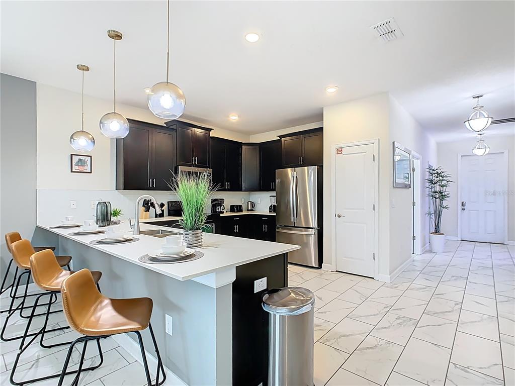 2925 Fable Street Kissimmee, FL 34746 - Photo 11 of 56 a kitchen with stainless steel appliances a stove a refrigerator a sink dining table and chairs with wooden floor