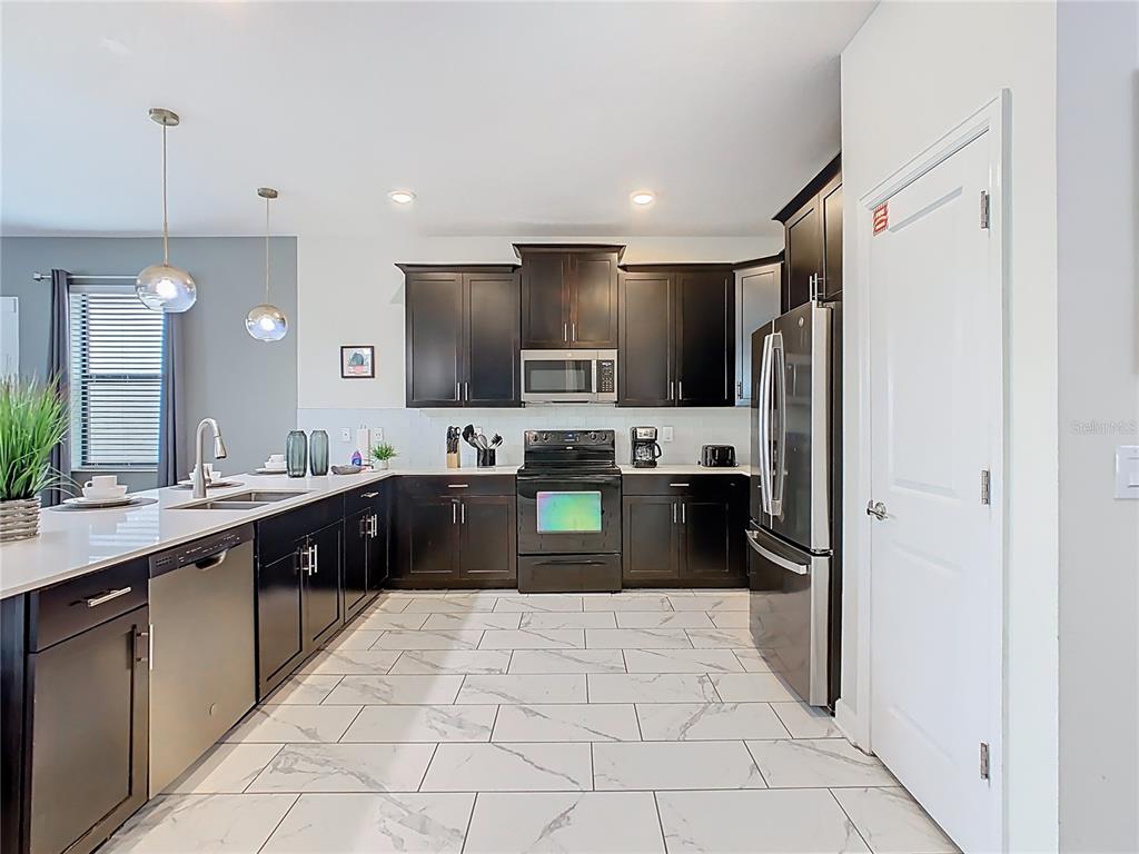 2925 Fable Street Kissimmee, FL 34746 - Photo 8 of 56 a large kitchen with a large counter top a refrigerator and a sink