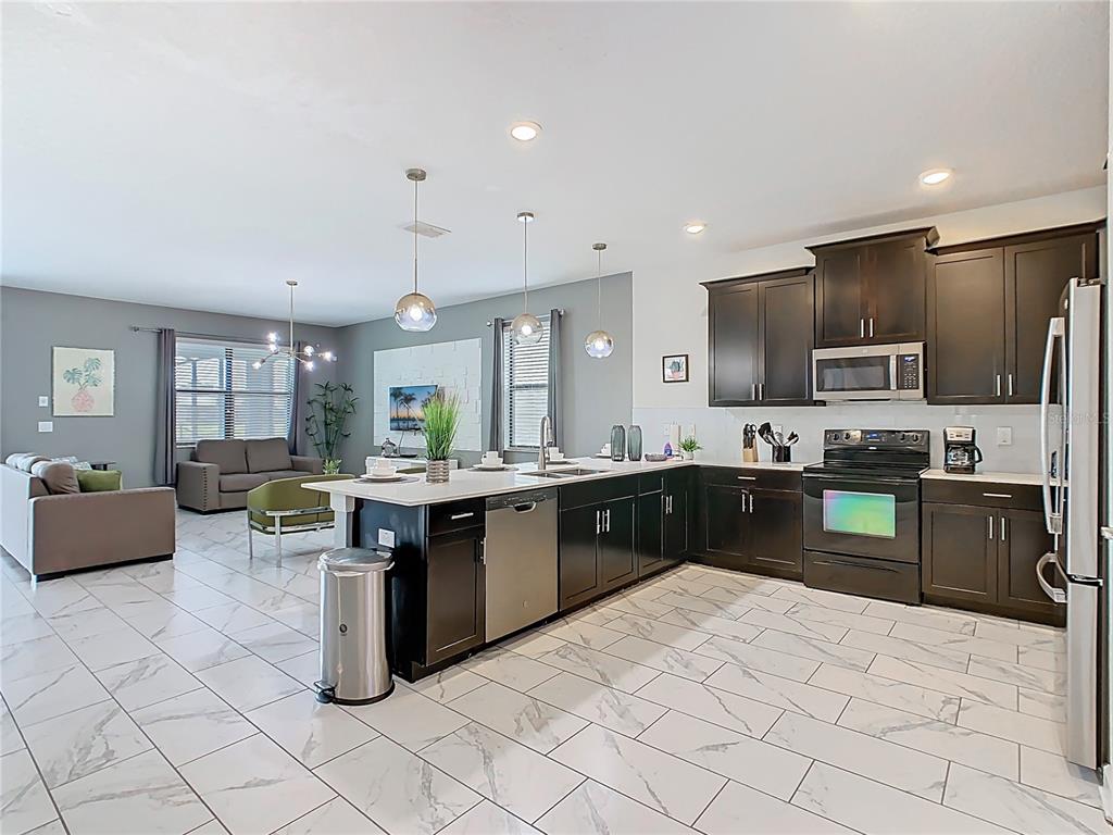 2925 Fable Street Kissimmee, FL 34746 - Photo 9 of 56 a large kitchen with kitchen island a sink a counter space and living room