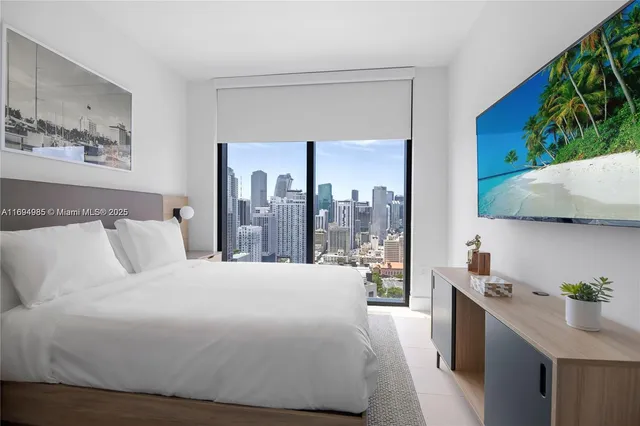 a bedroom with a large bed and a potted plant on the dresser