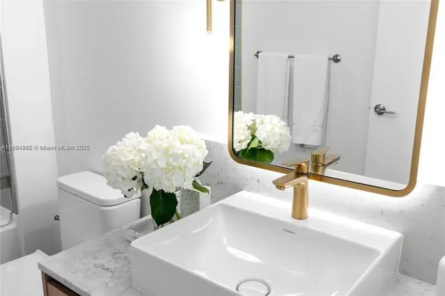 a bathroom with a sink a toilet a mirror and bathtub