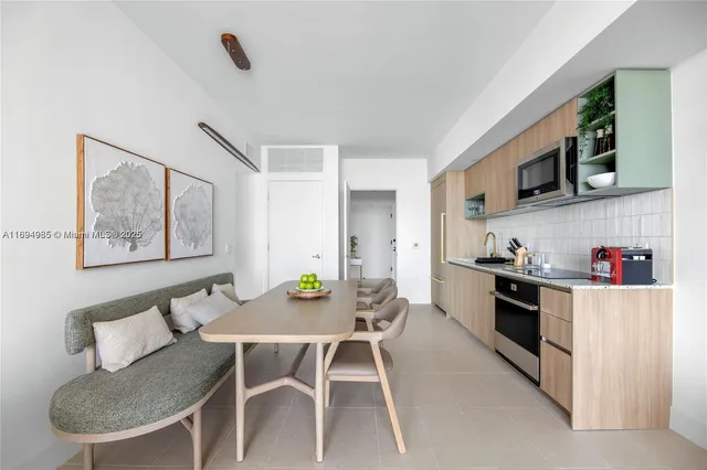 a kitchen with stainless steel appliances kitchen island granite countertop a table chairs and a refrigerator