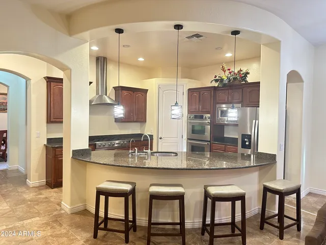 a kitchen with kitchen island granite countertop a table chairs sink and refrigerator