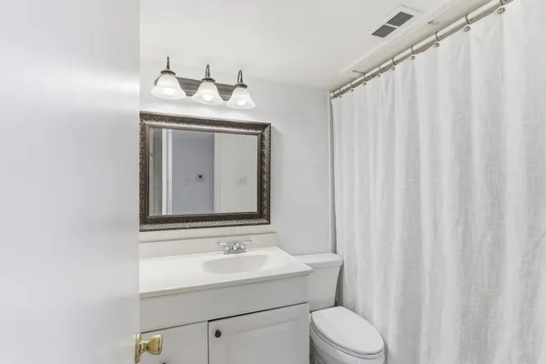 a bathroom with a toilet sink vanity and mirror