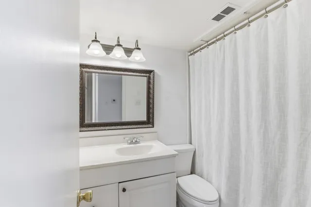 a bathroom with a toilet sink vanity and mirror