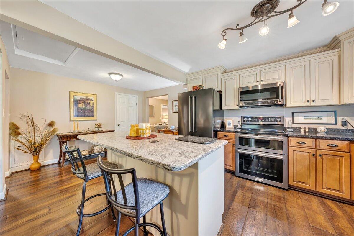 4099 Daugherty Road Salem, VA 24153 - Photo 8 of 45 a kitchen with stainless steel appliances granite countertop a stove top oven a refrigerator a dining table and chairs with wooden floor
