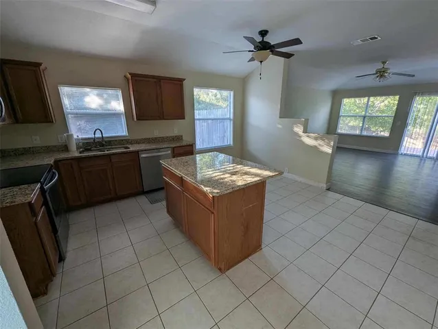 a kitchen with stainless steel appliances granite countertop a stove top oven a sink a counter space and cabinets