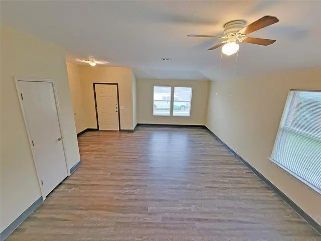 a view of an empty room with window and wooden floor